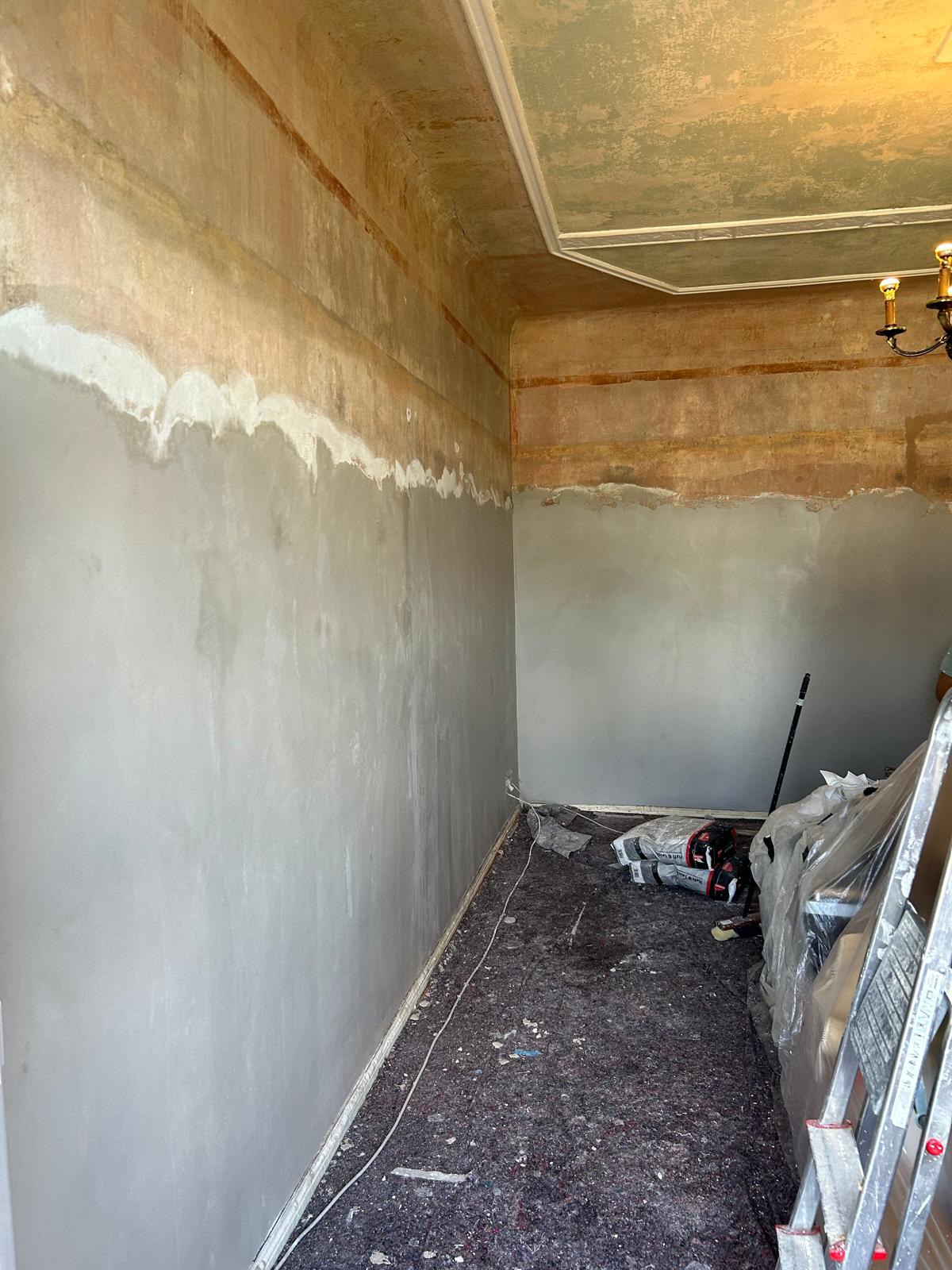 Wandfläche im Altbau während der Vorbereitung: unten frisch gespachtelt, oben noch alte Beschichtung