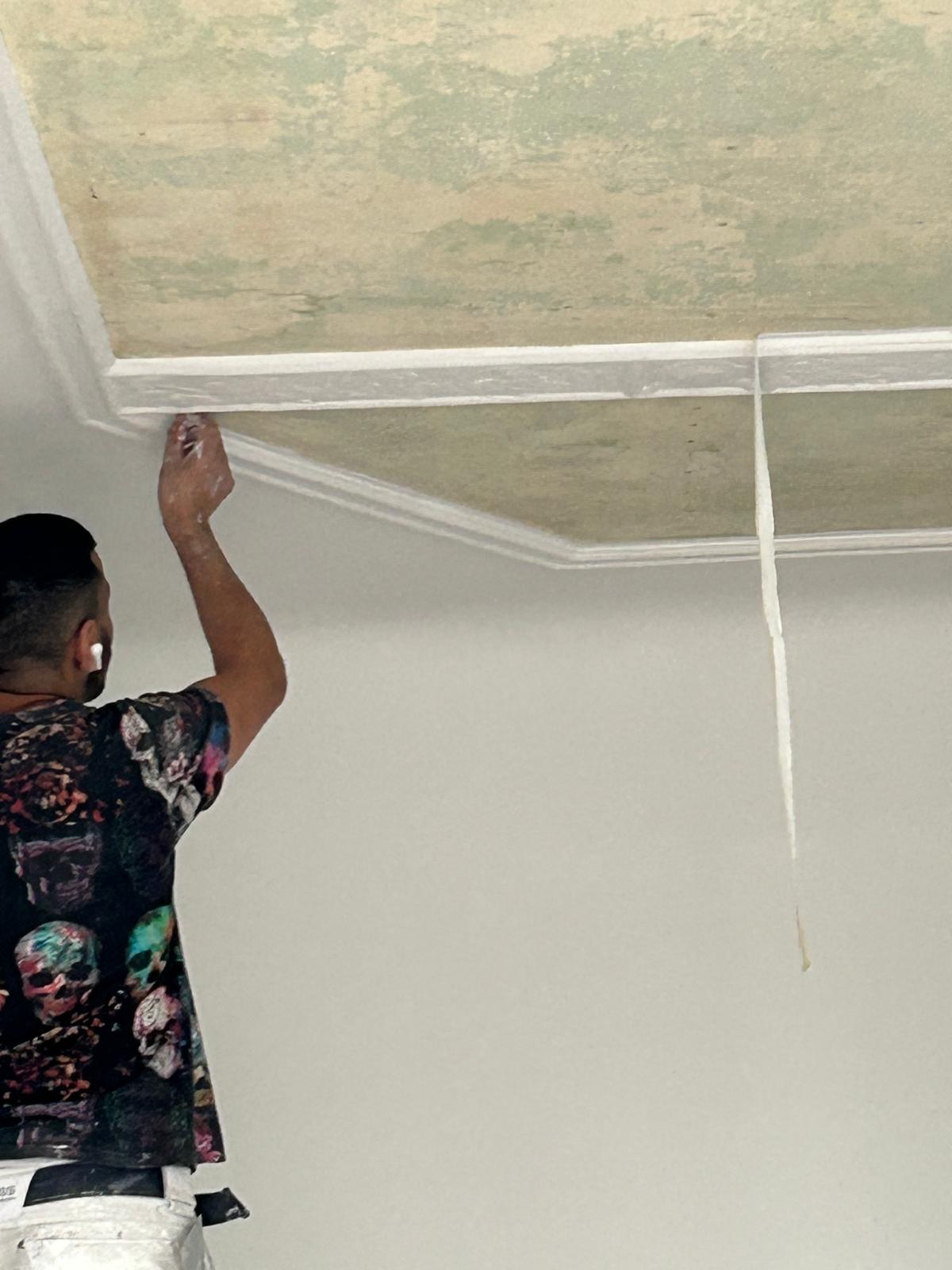 Mitarbeiter von Planada Bau bei der sorgfältigen Überarbeitung einer Stuckleiste an der Decke