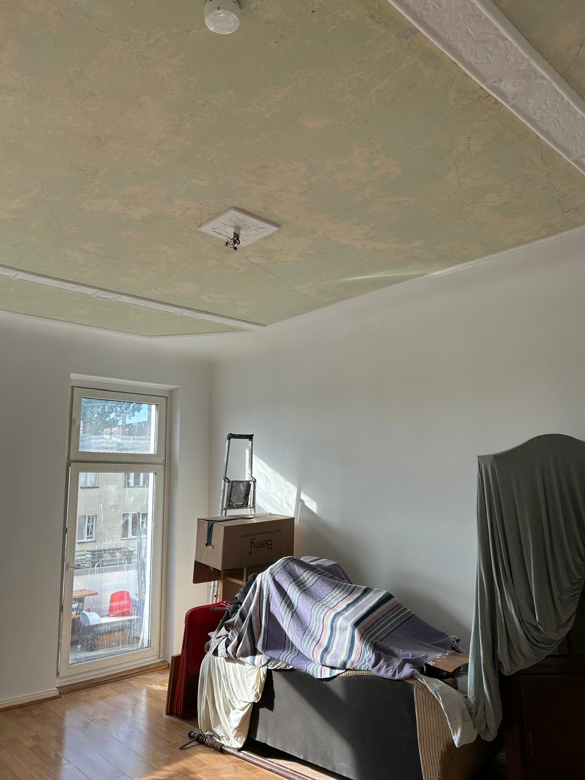 Altbauzimmer nach der Sanierung: glatt gespachtelte, frisch weiß gestrichene Wände bei erhaltener Stuckdecke